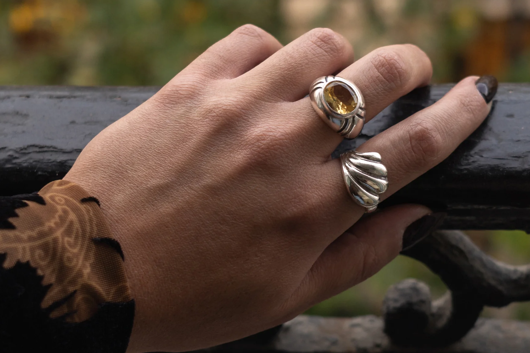 The fingers of a woman wearing two silver rings