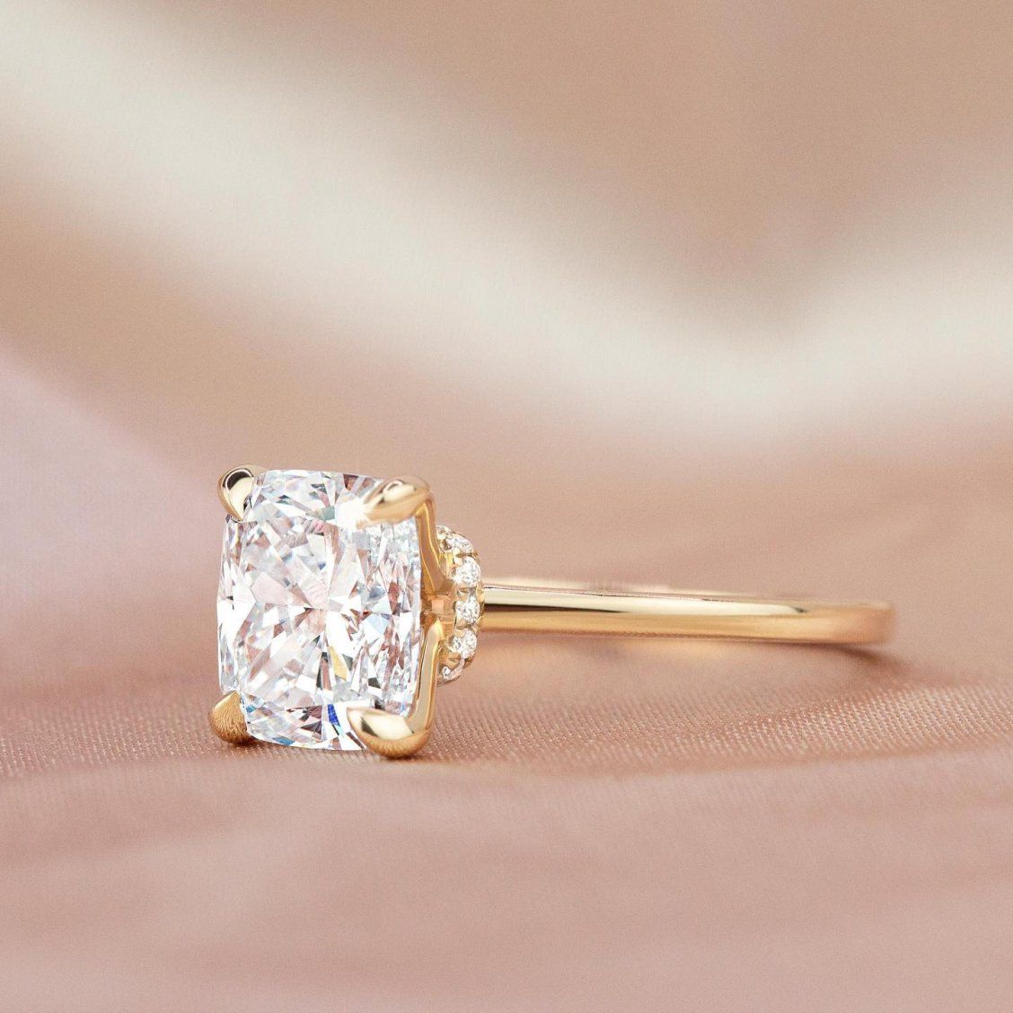 To either side of the center stone, this exquisite setting has two thin precious metal bands with pear-shaped diamond accents