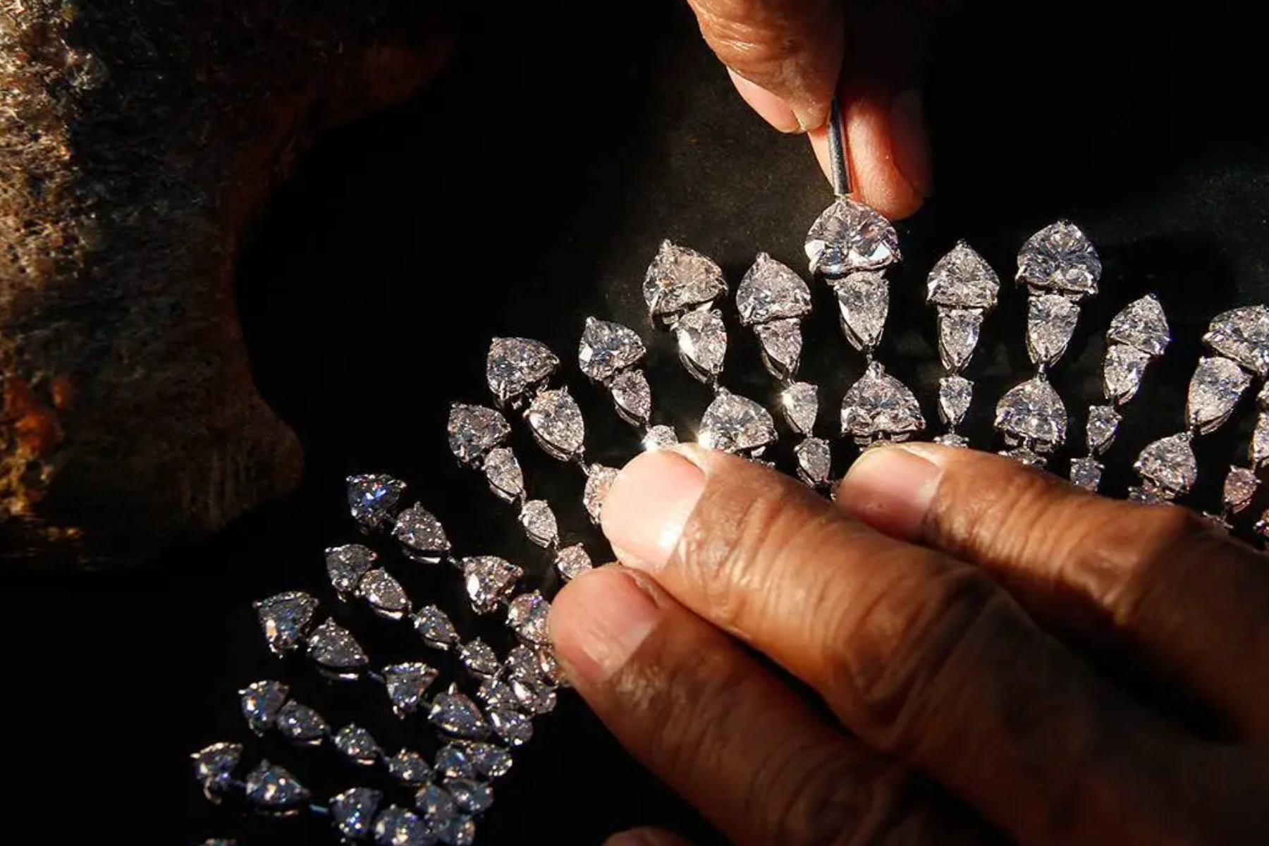 A man's hand fixing a diamond necklace