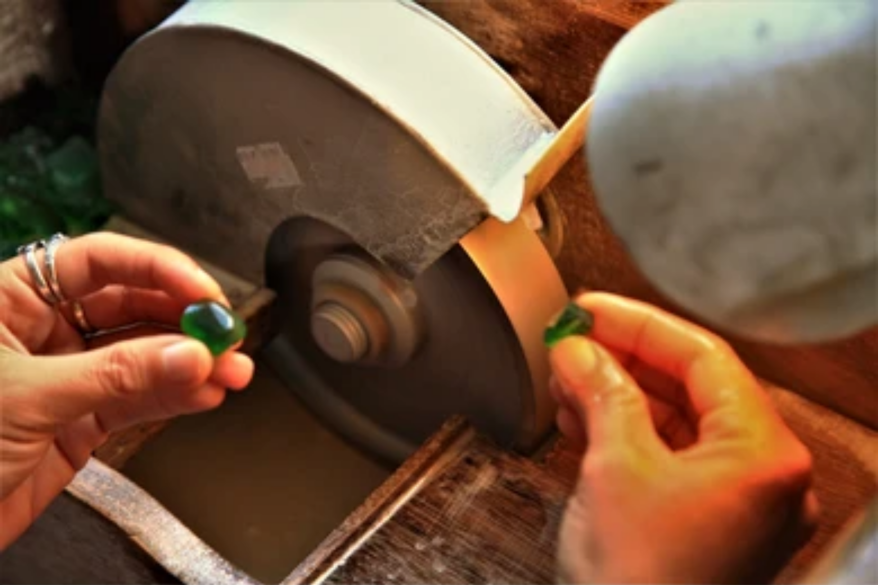 A green stone is directly putĀ into a cutting machine while a well-polished green stone is held in the other hand as a reference