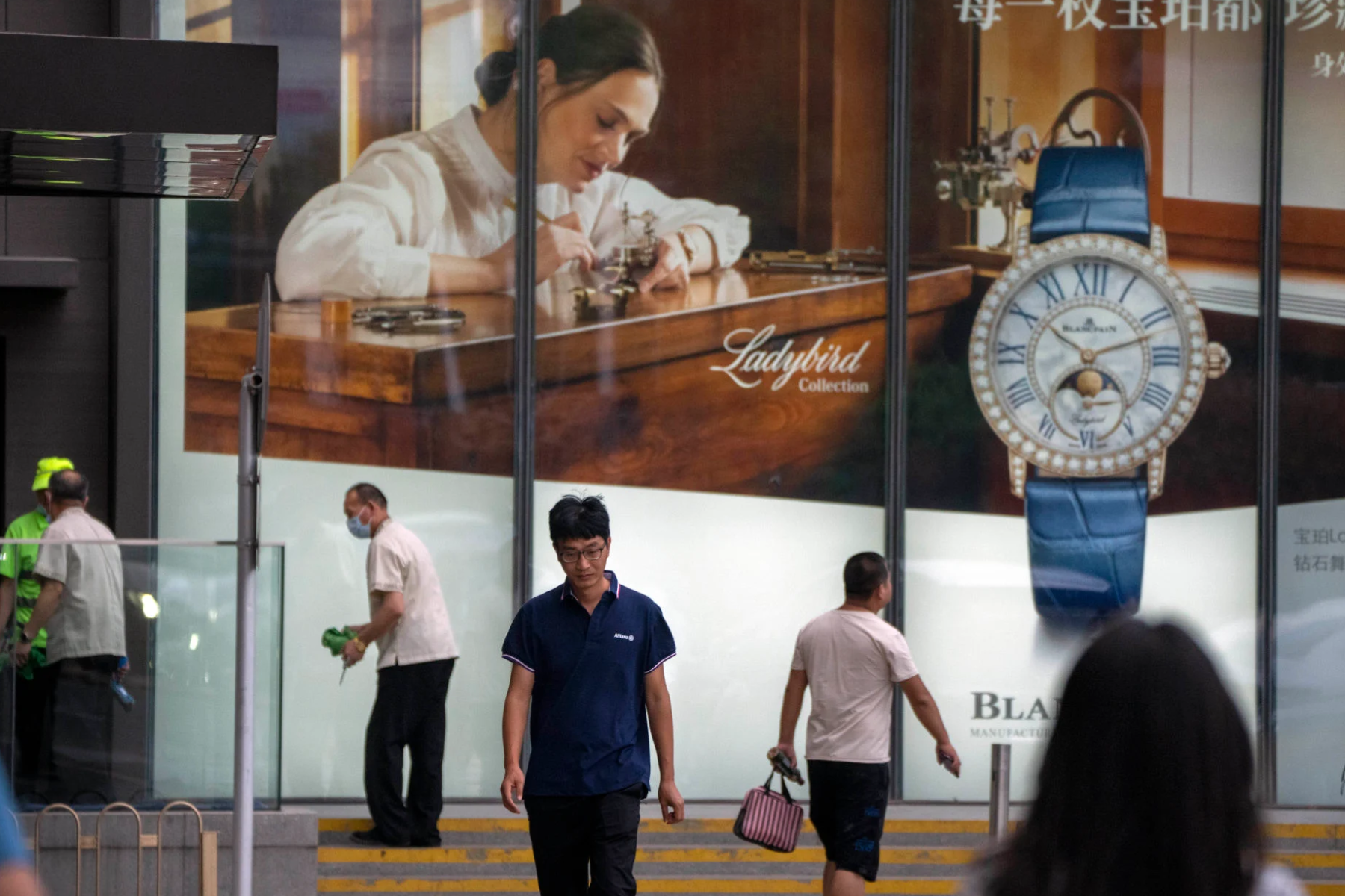 People walk past a billboard for Swiss luxury watch retailer Blancpain at a shopping centre in Beijing in June