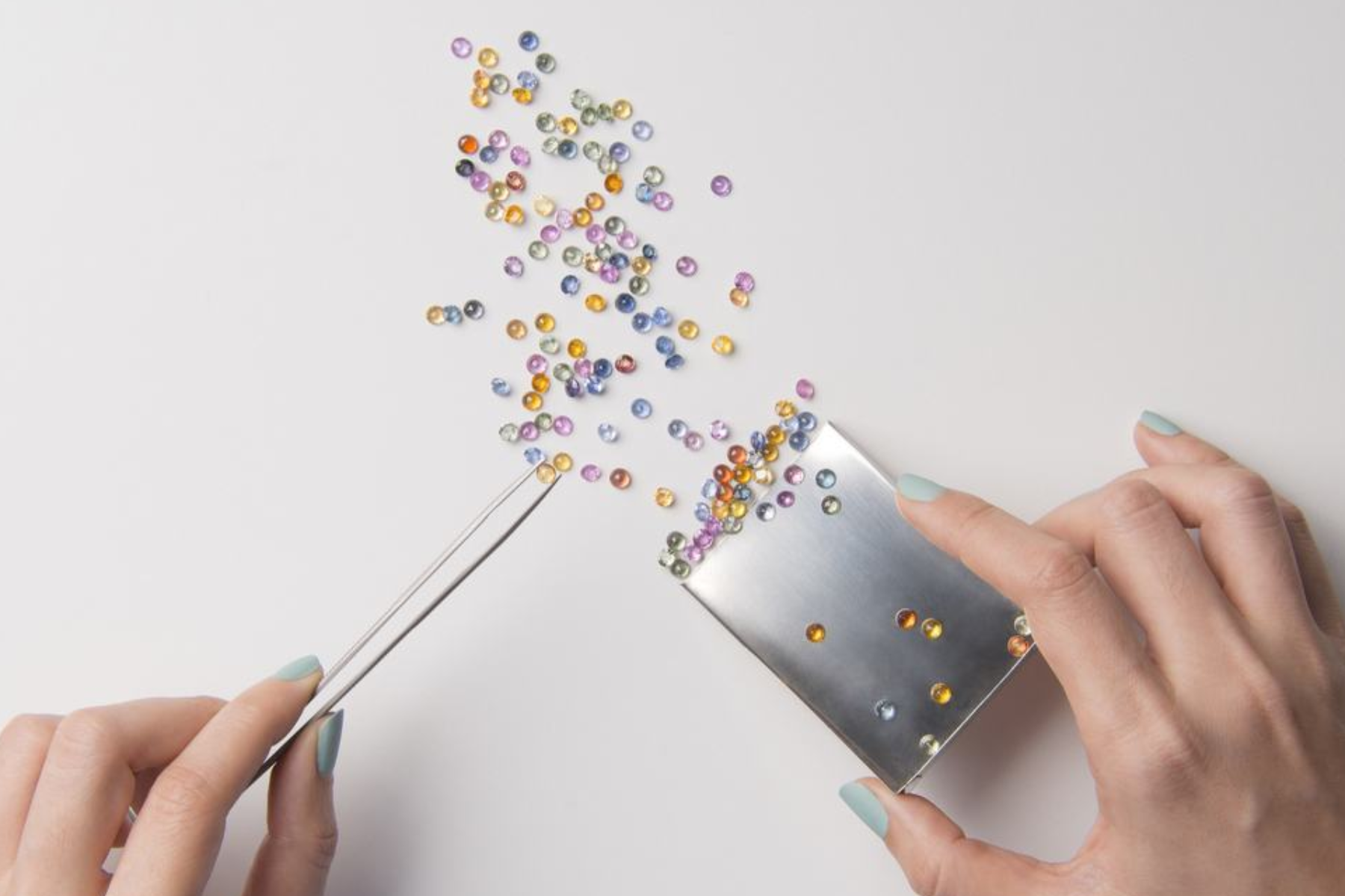 A woman's hand selects small gemstone pieces