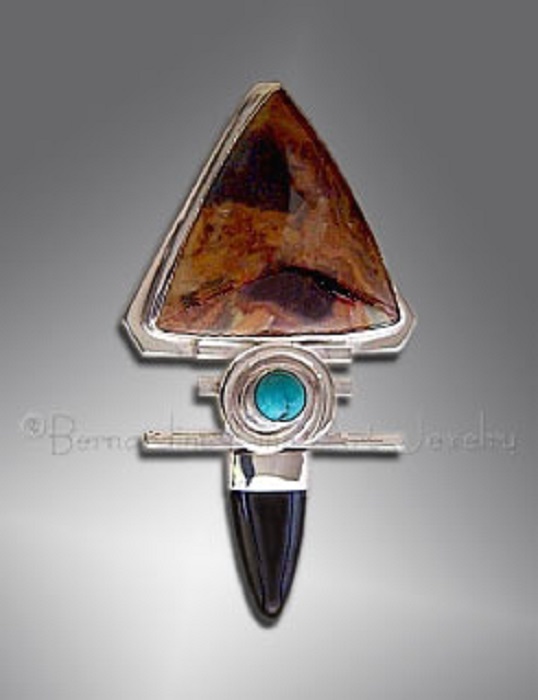 A silver pendant with a small round turquoise between a big triangular pietersite and a pointed black onyx