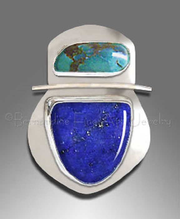 A silver pendant with a large lapis lazuli shaped like a heraldic shield and an irregular-shaped turquoise