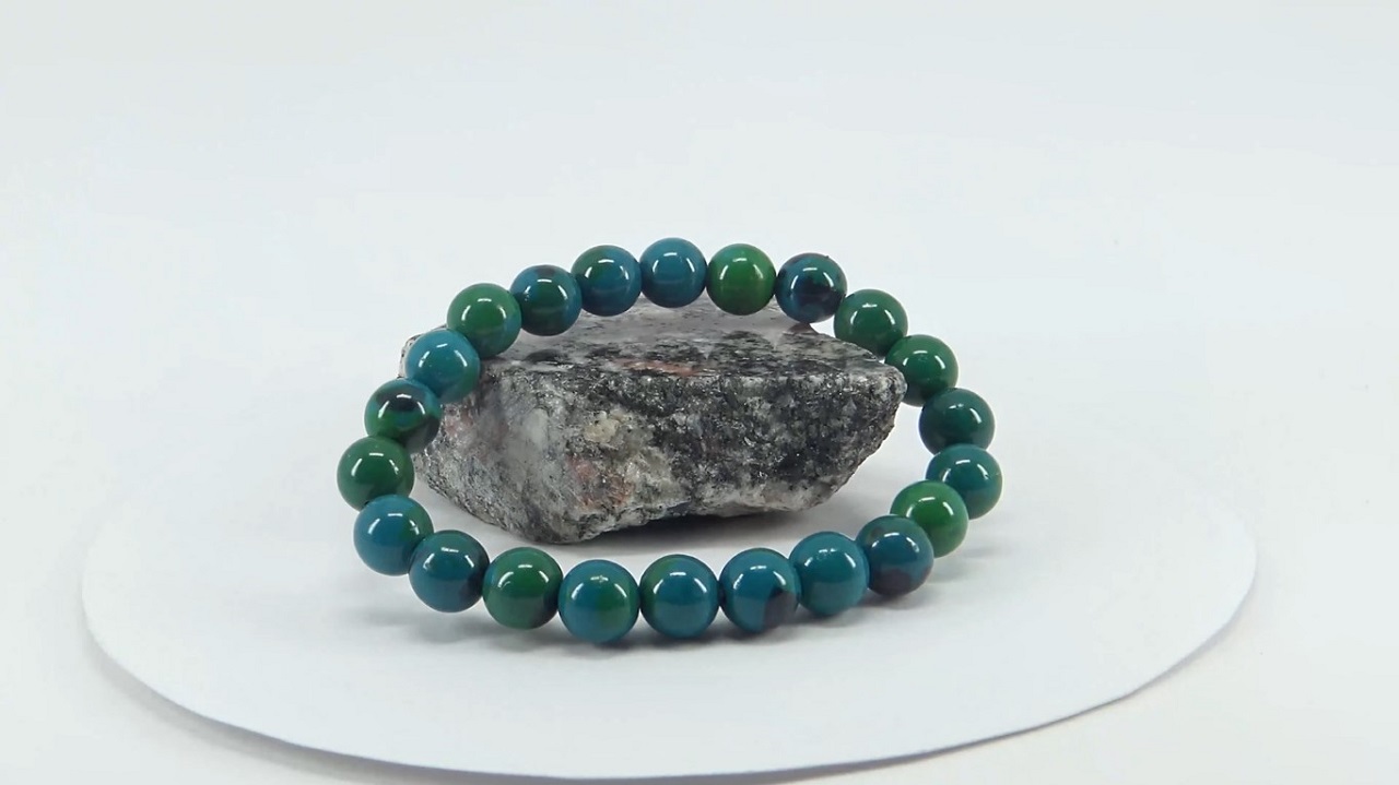 A chrysocolla bracelet with 22 pieces of shiny round blue-green chrysocolla placed on a small piece of rock